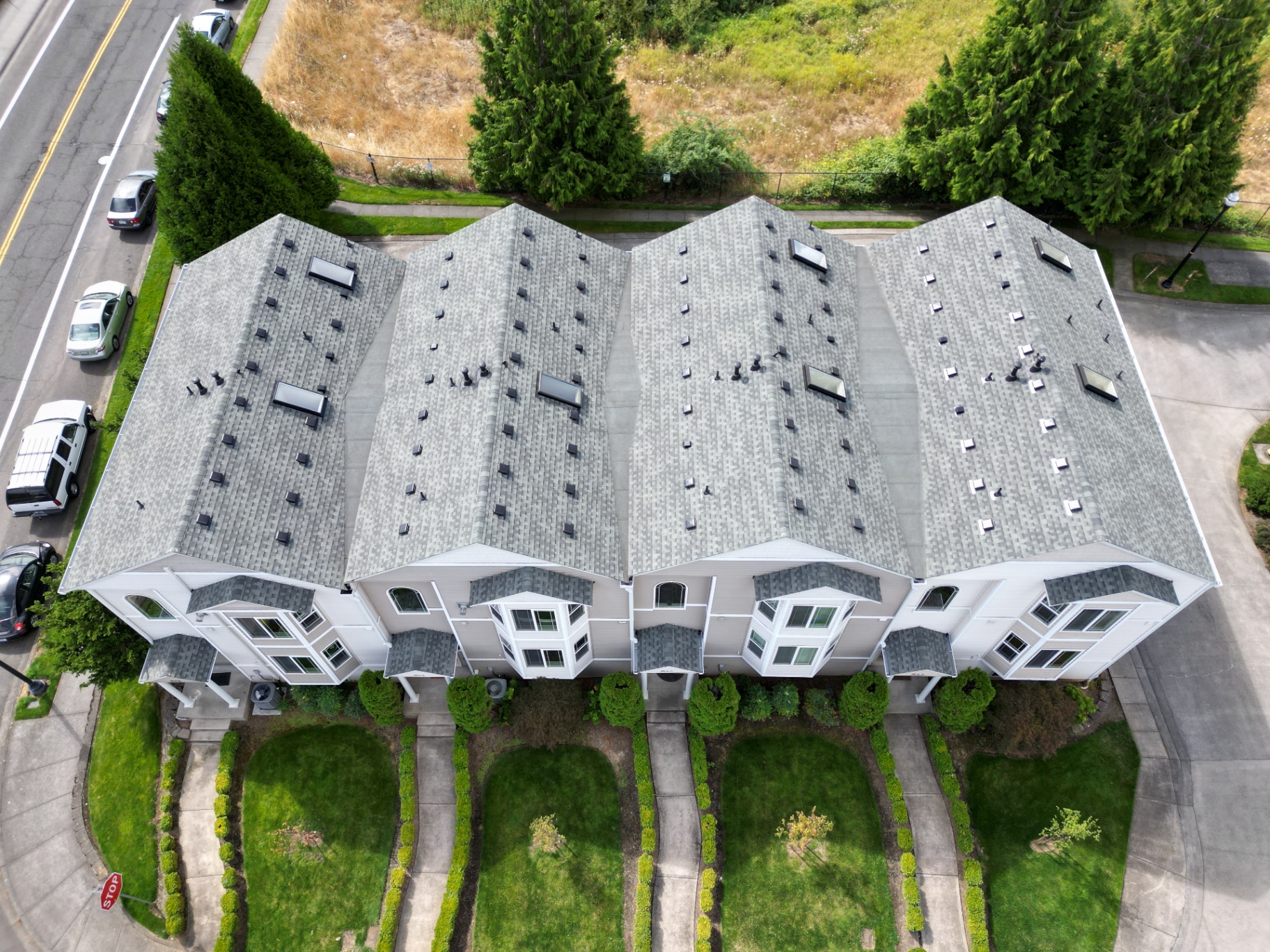Aerial view of multiple connected townhomes with matching new shingle roofs