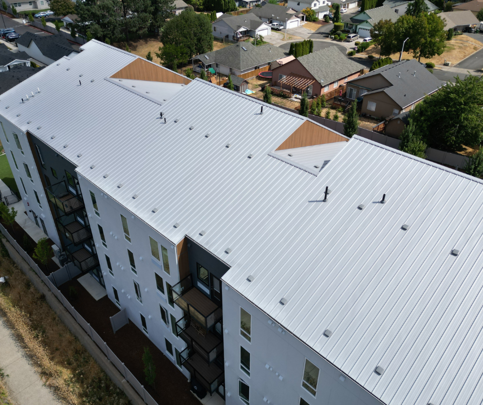 Large multifamily building with a bright white standing seam metal roof