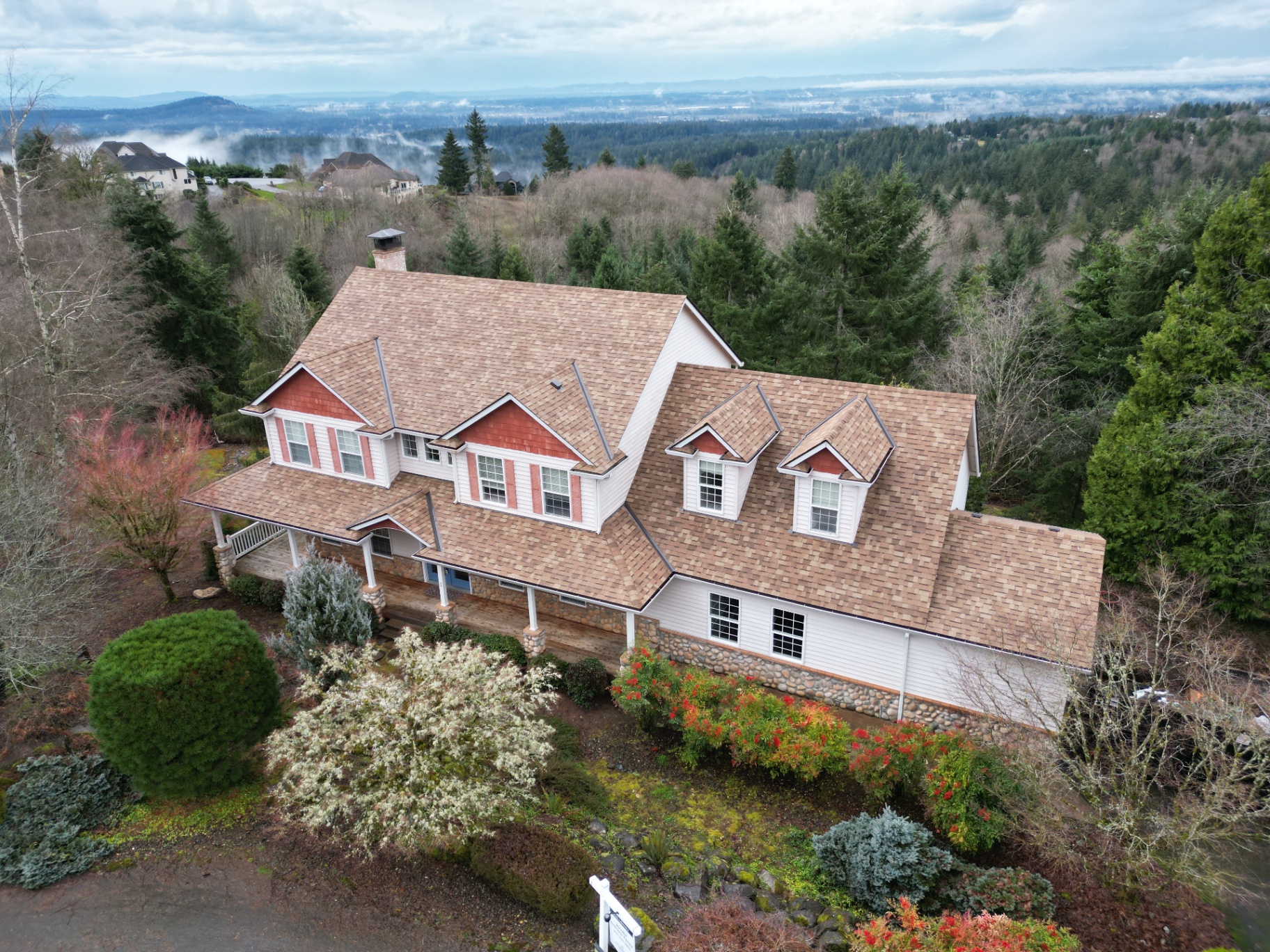 Large residential estate with a warm-toned architectural shingle roof viewed from above