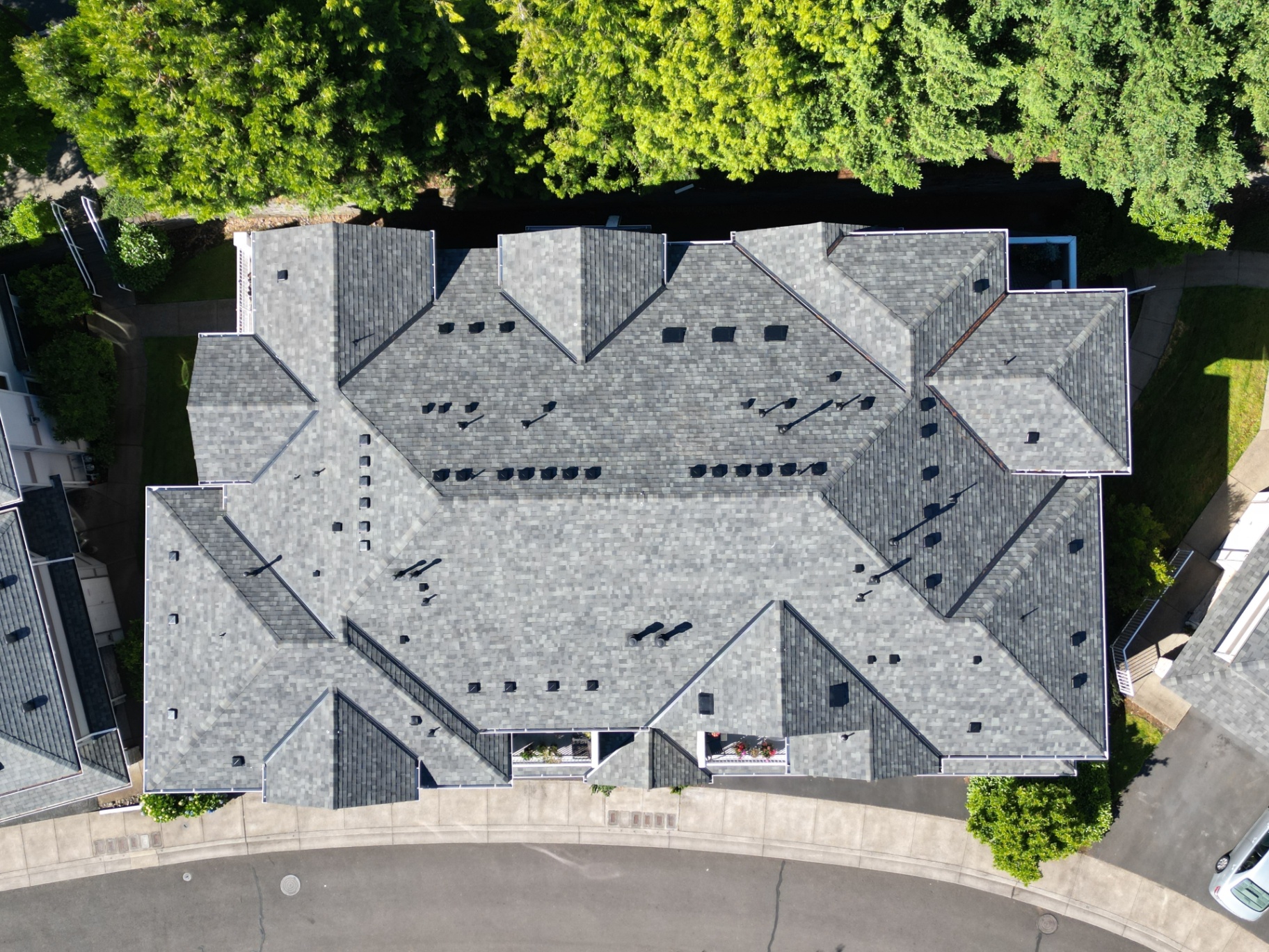 Top-down aerial view of a completed gray shingle roof with multiple ridges and valleys